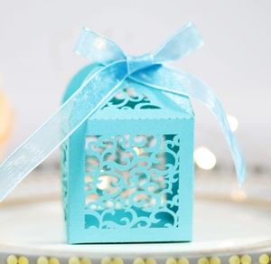 Close-up of light blue laser-cut gift box featuring intricate swirl patterns and ribbon bow
