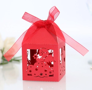 Close-up of red house-shaped gift box with hollow angel pattern and silk ribbon