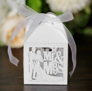 Close-up of white laser-cut wedding favor box with Mr & Mrs motif and ribbon