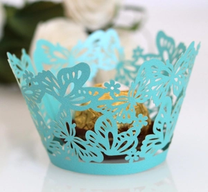 Macro view of laser-cut butterfly and floral patterns on cyan paper cupcake wrapper