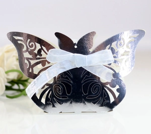Close-up of laser-cut silver butterfly wedding favor box with white satin ribbon detail