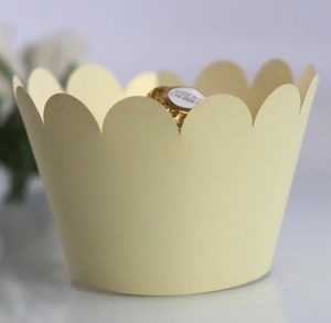 Macro detail of scalloped cream paper cupcake wrapper with golden reflective finish