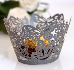 Detail of laser-cut butterfly cupcake wrappers in shimmering silver paper for weddings