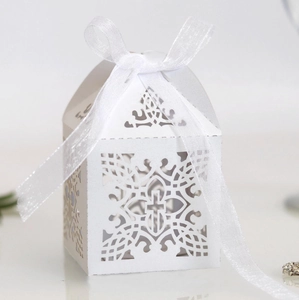 Macro shot of white laser-cut favor box with cross pattern and white organza ribbon bow