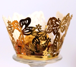 Laser-cut golden cupcake wrapper featuring hollow butterfly and flower patterns