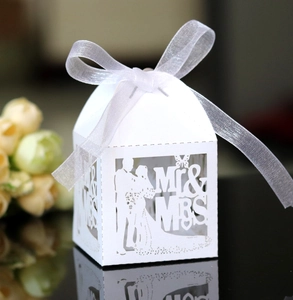 Macro detail of laser-cut Mr & Mrs wedding favor box with elegant white ribbon bow