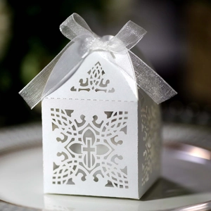 Macro shot of laser-cut cross wedding candy box with elegant white organza ribbon