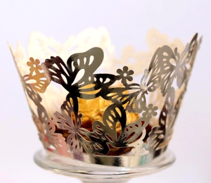 Macro shot of laser-cut cupcake wrappers with intricate golden butterfly patterns