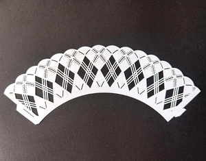 Macro view of white argyle laser-cut cupcake wrapper with intricate lattice detail