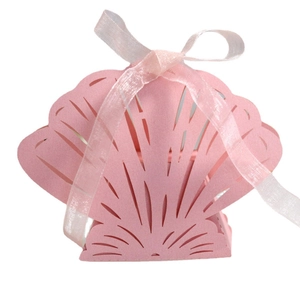 Pink shell-shaped laser cut wedding favor box with white ribbon bow on white background