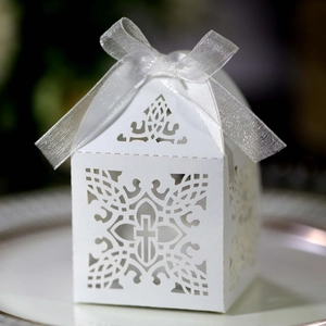 Close-up of white laser-cut wedding favor box with cross pattern and silver ribbon bow