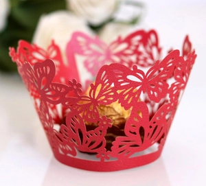 Macro shot of red laser-cut cupcake wrapper with butterfly patterns for party decor