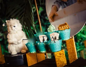 Laser-cut turquoise cupcake wrappers with BABY cake toppers for forest baby shower party decor