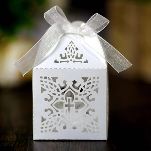 Macro detail of laser-cut white favor box with elegant cross pattern and satin ribbon