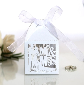 Macro shot of white laser-cut wedding favor box with Mr & Mrs silhouette and silk ribbon
