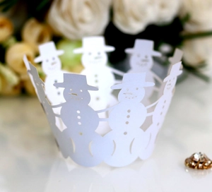 Detail of laser-cut white cupcake wrappers with festive snowman pattern for Christmas