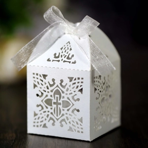 Detail of laser-cut white cross favor box with silver ribbon for wedding party favors