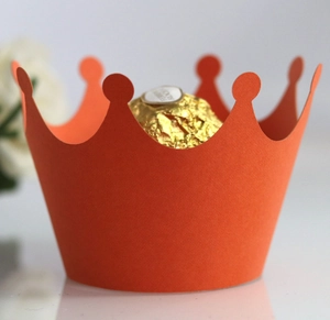 Detailed macro view of an orange crown-shaped paper cupcake liner holding a chocolate