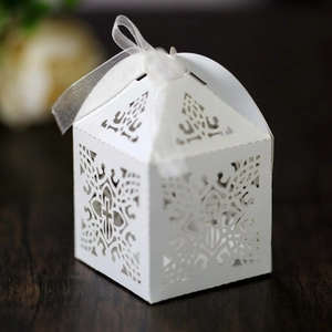 Macro detail of laser-cut white favor box with elegant cross pattern and silk ribbon