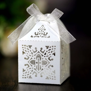 Detail of laser-cut cross gift box in white paper with silver organza ribbon bow