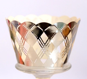 Macro view of laser cut golden cupcake wrappers with diamond lattice and wavy edges