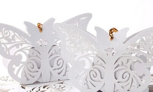 Macro detail of white laser-cut butterfly wedding favor box with golden ribbon tie