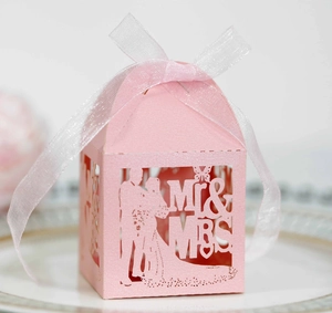 Detail of pink laser-cut wedding favor box with Mr & Mrs text and organza ribbon