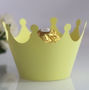 Close-up of laser-cut crown cupcake wrappers in vibrant yellow for party dessert display