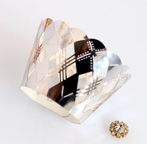 Detail of silver laser-cut cupcake wrapper with intricate diamond patterns and mirror finish
