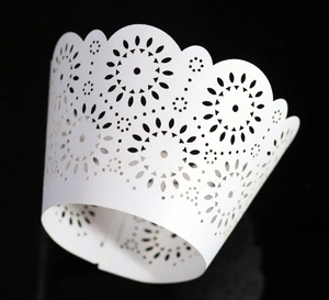 Macro detail of white laser-cut cupcake wrappers with floral sunflower hollow pattern