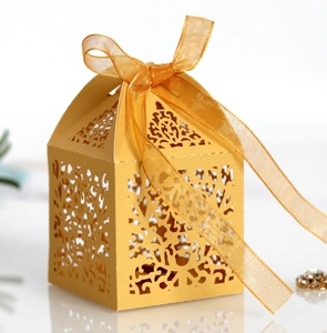 Detailed laser-cut gift box in golden hue with elegant organza ribbon and vine patterns