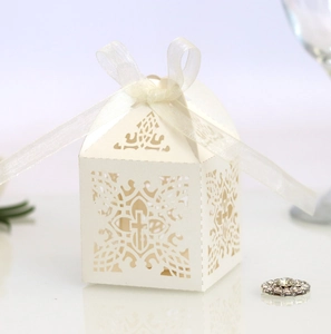 Detail of laser-cut cross pattern on white paper wedding favor box with ribbon