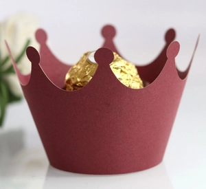 Close-up of laser-cut crown-shaped burgundy cupcake wrappers for festive party desserts