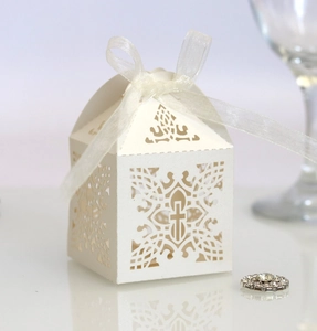 Close-up of laser-cut cross pattern on ivory wedding candy box with organza ribbon