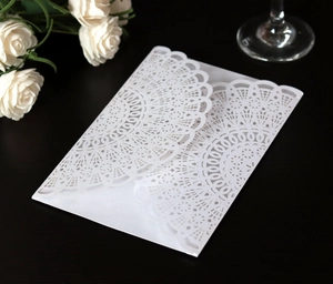 Close-up of white laser-cut lace wedding invitation with intricate floral hollow design