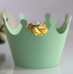 Detail of a mint green crown-shaped paper cupcake wrapper with a golden chocolate ball