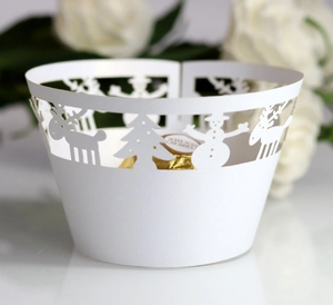 Laser-cut white cupcake wrapper with reindeer and snowman hollow patterns for Christmas