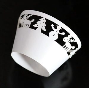 Macro detail of laser-cut Christmas cupcake wrapper with reindeer and snowman patterns