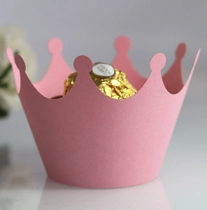 Detailed close-up of pink crown-shaped paper cupcake wrappers used for festive dessert décor