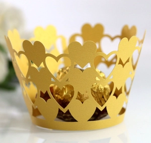 Close-up of golden hollow heart lace cupcake wrapper with laser-cut metallic finish