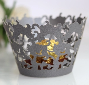 Macro detail of laser-cut pearlescent paper cupcake wrapper with floral vine patterns