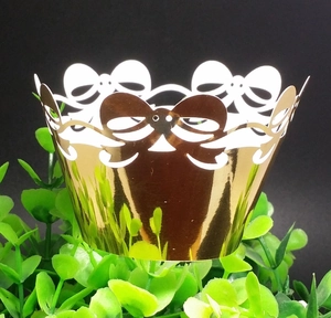 Close-up of golden laser-cut cupcake wrappers with elegant hollow bow-knot design