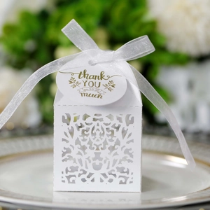 Macro view of white laser-cut wedding favor box with ribbon and thank you tag