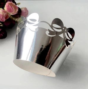 Macro shot of silver mirror laser-cut cupcake wrappers with elegant hollow bow patterns