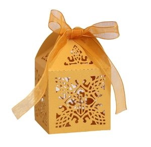 Detail of laser-cut cross patterns on golden gift box with a matching ribbon bow