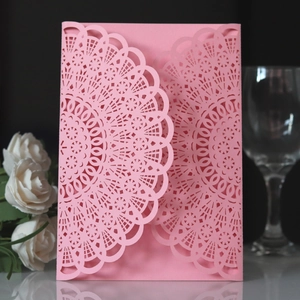 Detail of pink laser-cut wedding invitation with lace pattern and elegant decor