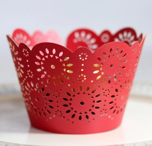 Macro detail of red laser-cut floral cupcake wrappers with pearlescent hollow design