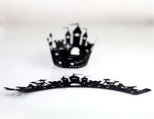 Detail of laser-cut black castle and crown cupcake wrappers with intricate hollow patterns
