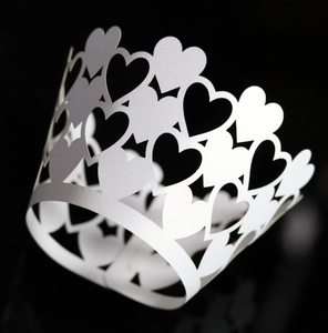 Detailed laser-cut heart patterns on a white paper cupcake wrapper for wedding decor