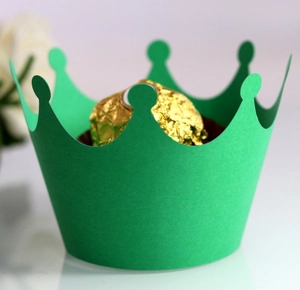 Detail of green crown laser cut cupcake wrapper with a gold chocolate truffle inside